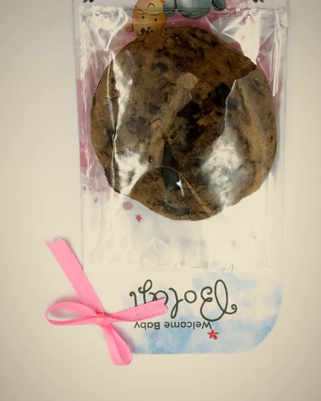 A Boxx65 Sweet Token for a baby welcome, with a pink ribbon